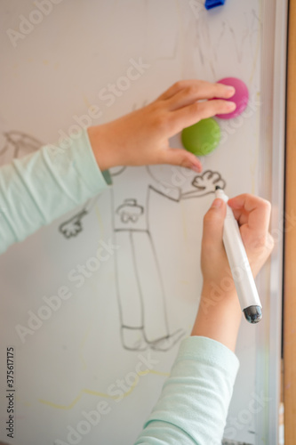 Little girl is writing on the white board