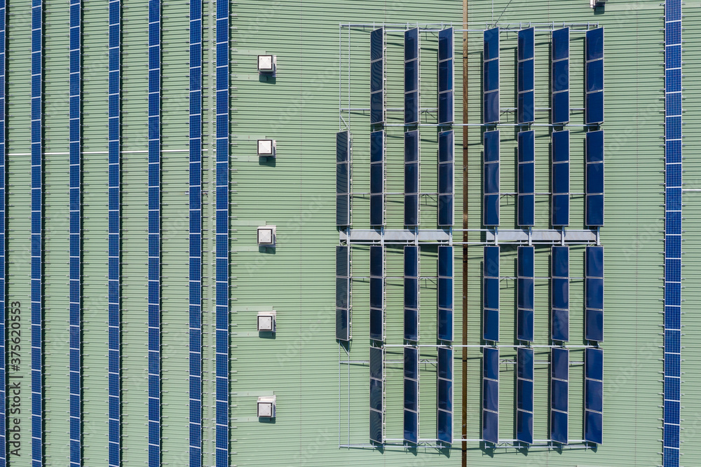 Solar panels and hot water heaters intalled on the building roof, aerial drone top down view