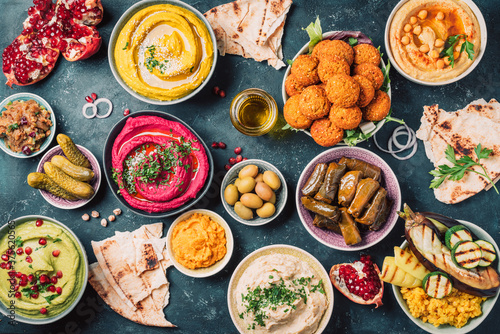 Arabic traditional cuisine. Middle Eastern meze with pita, olives, colorful hummus, falafel, stuffed dolma, babaganush, pickles, vegetables, pomegranate, eggplants. Mediterranean appetizer party idea photo