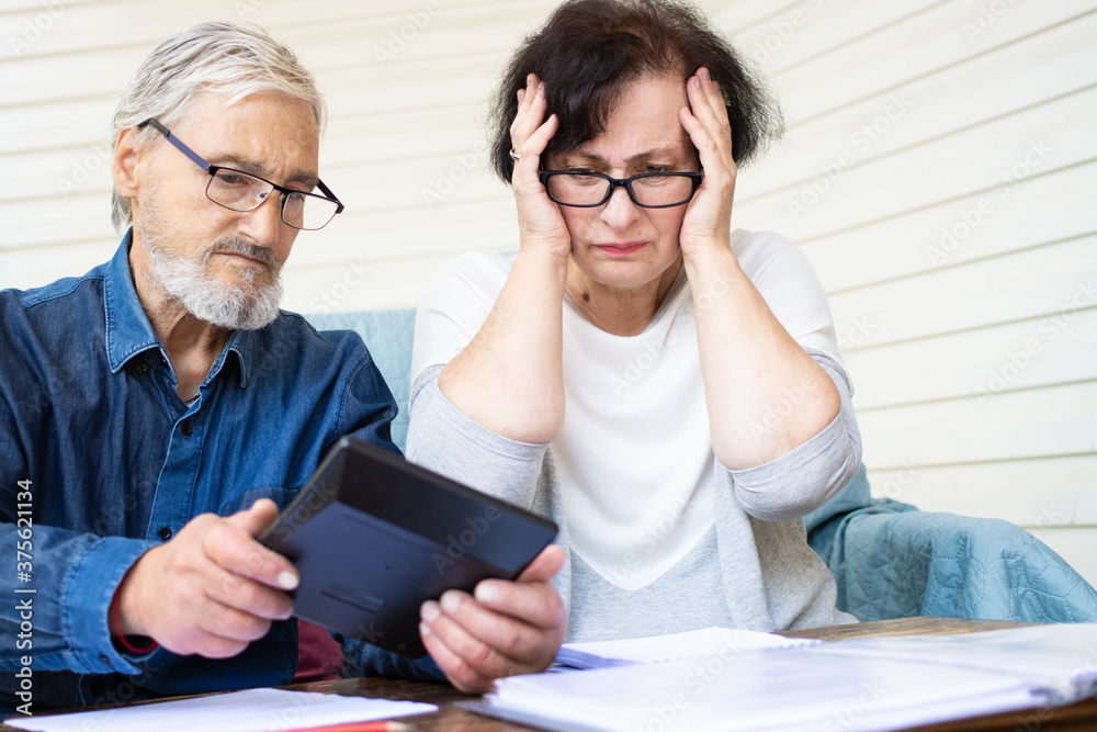 Scared and worried senior couple looking at calculator, counting bank loan payment, calculating bills managing domestic finances. Worried about bankruptcy or money problem. Little savings concept Scared and worried senior couple looking at calculator, counting bank loan payment, calculating bills managing domestic finances. Worried about bankruptcy or money problem. Little savings concept