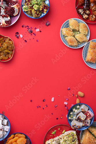 Traditional turkish delight on red background. Top view. Flat lay. Copy space. Arab dessert, baklava, halva, rahat lokum, sherbet, nuts, pistachios, dates, raisins, dried apricots, churchkhela.