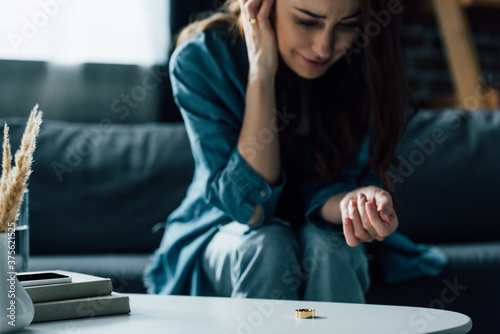 selective focus of golden ring on coffee table near upset woman  divorce concept