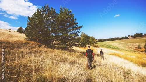 Rear view of unrecognizable people with backpack hiking in the n