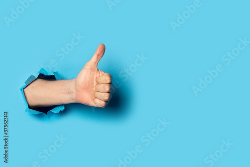 Foto Male hand makes a hand up gesture on a blue background