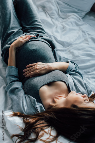 overhead view of pregnant woman suffering from pain on bed