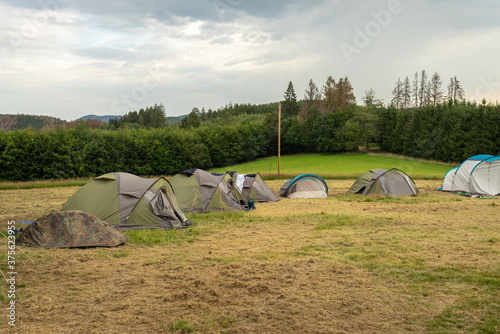 Scout camping. Army military tent close up in the base camp. Lots of tents stand on a field against a green forest. 