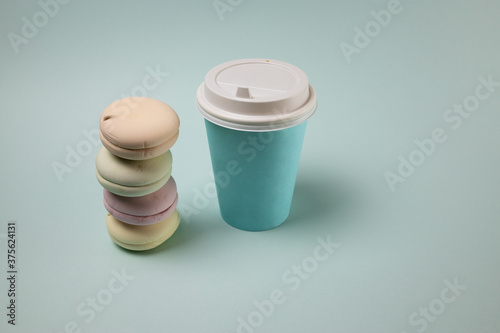 Paper cup with coffee and macaroons on a blue background