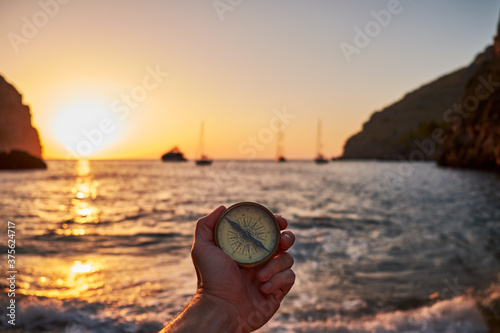 male hand holding compass in the sea