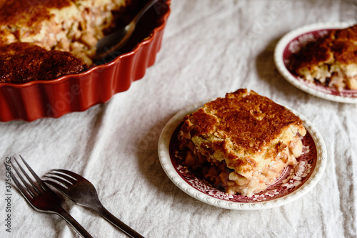 Apple and Cheese Cobbler Crisp. Cobbler or Crumble dessert with apples in ceramic baking form on beige linen table. Selective focus photo