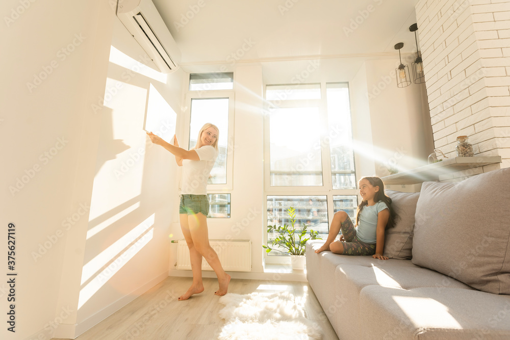 mother and daughter hangs a large photo canvas at home mother and daughter hangs a large photo canvas at home