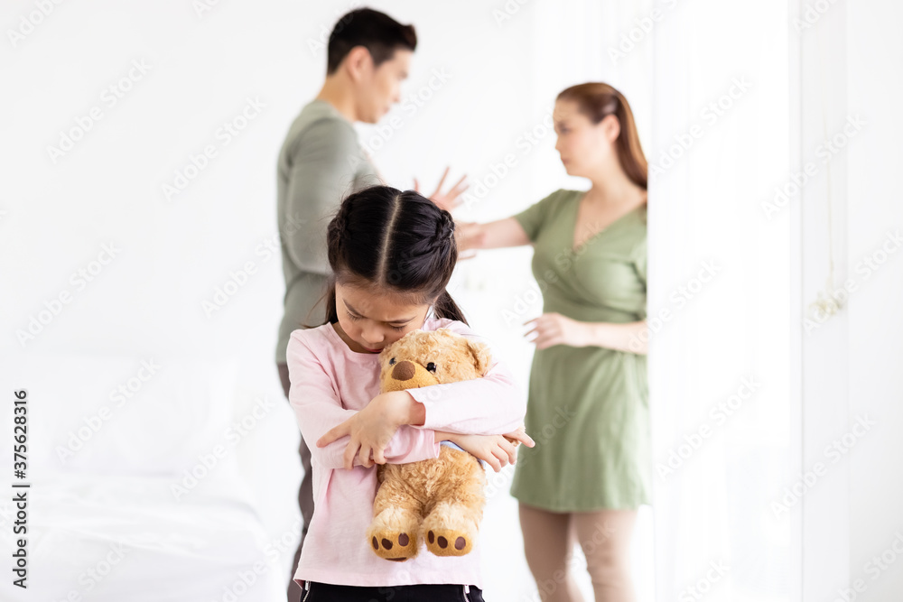 Asian little child girl sitting alone hug bear doll emotion unhappy and sadness because father and mother quarrel.
