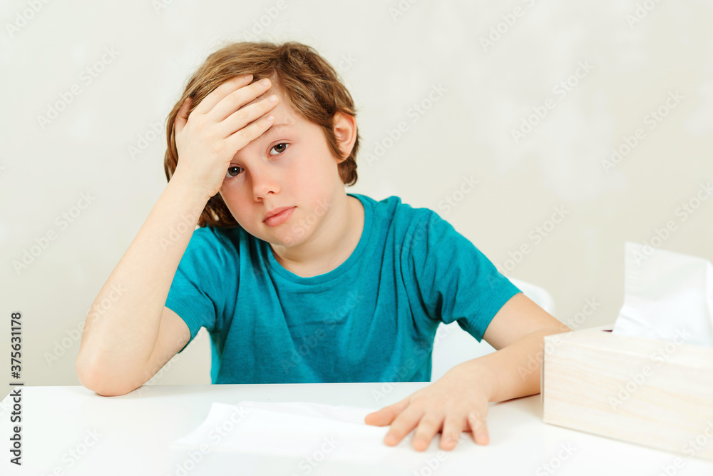 Schoolboy has headache during lessons. Sick boy sitting at the desk. Boy has a virus, runny nose and headache. Healthcare and childhood. Schoolboy has headache during lessons. Sick boy sitting at the desk. Boy has a virus, runny nose and headache. Healthcare and childhood.