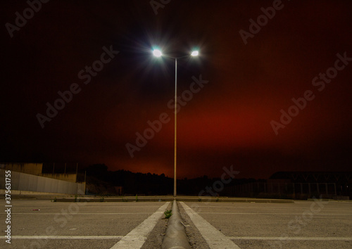 farola solitaria en parquing vacío por la noche con cielo rojo 