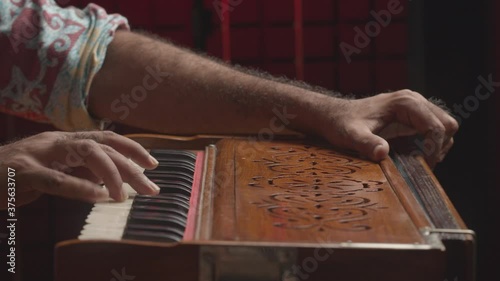 Music production studio. Creative world. Close up of an Indian man playing traditional instrument in the sound studio. Male person plays meditation music.