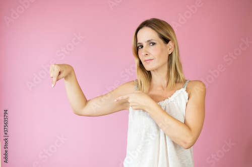 Beautiful woman pointing something on pink background