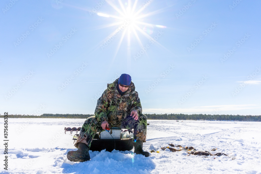 fisherman catches fish in winter on a bright Sunny day. winter sports, winter fishing fisherman catches fish in winter on a bright Sunny day. winter sports, winter fishing