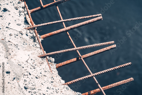 Rusty iron pins protrude from the concrete blocks of collapsing bridge from old age.