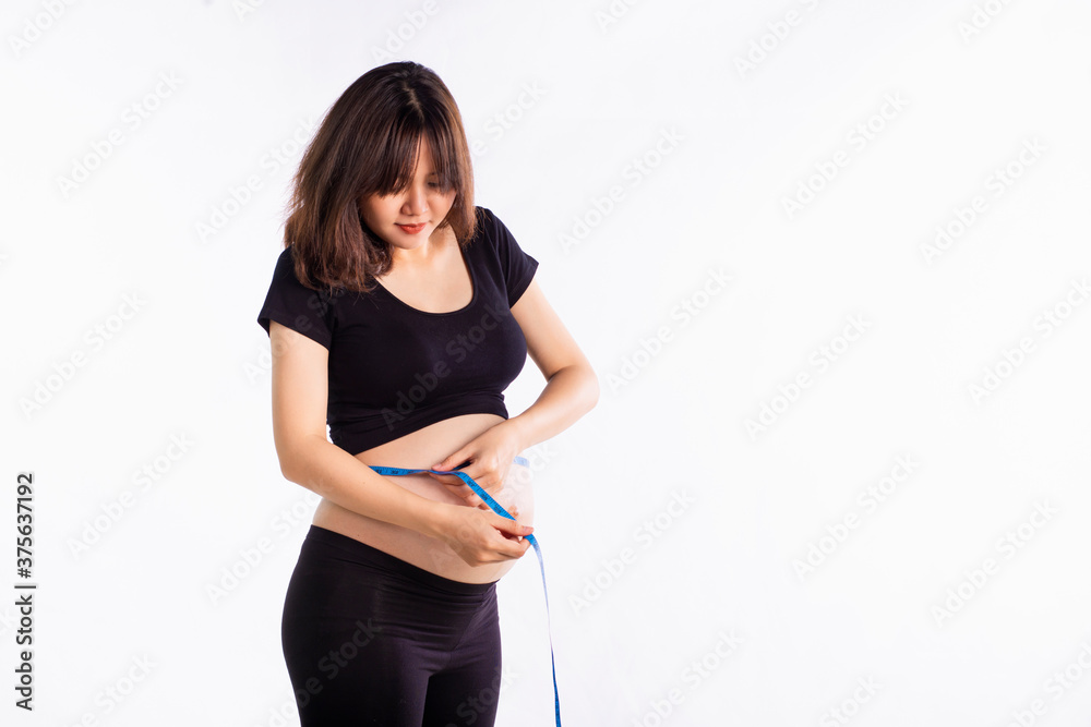 Beautiful pregnant asian woman measuring her belly on a white background. Copy space Beautiful pregnant asian woman measuring her belly on a white background. Copy space