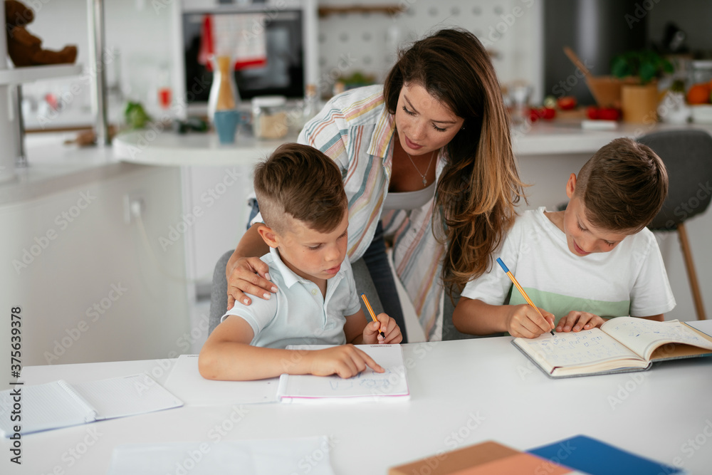 Mother helping her son with homework at home. Little boy learning at home.. Mother helping her son with homework at home. Little boy learning at home..