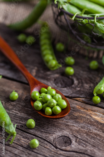 Fresh peas in wooden spoon on table