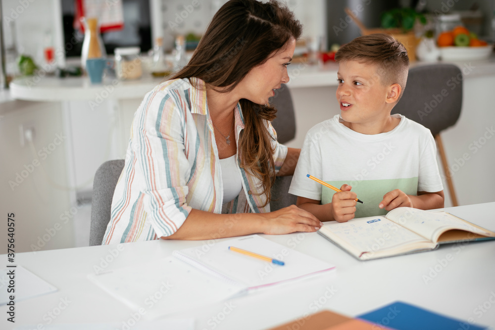 Mother helping her son with homework at home. Little boy learning at home.. Mother helping her son with homework at home. Little boy learning at home..
