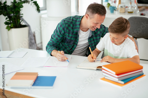 Father helping her son with homework at home. Little boy learning at home..