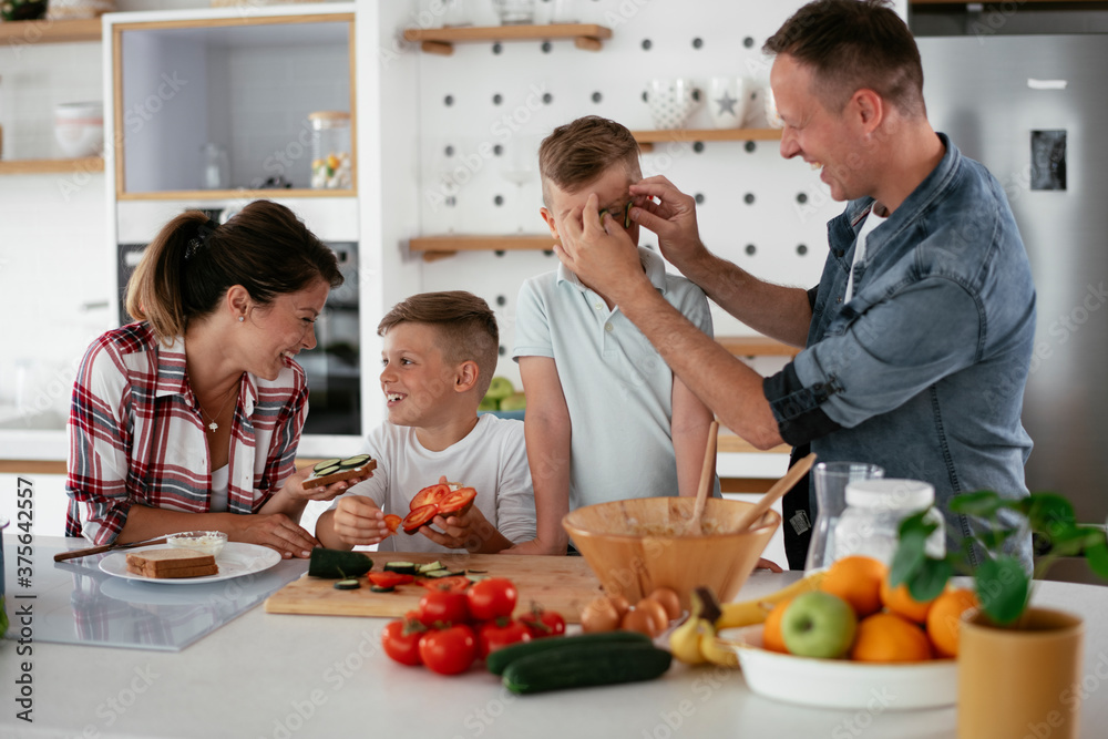 Mother and father making breakfast with sons. Young family preparing delicious food in kitchen. Mother and father making breakfast with sons. Young family preparing delicious food in kitchen.