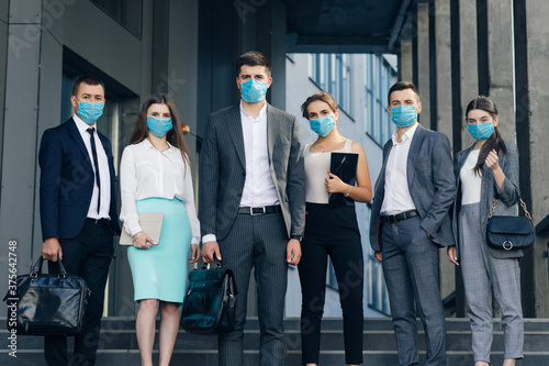 Corporate team portrait in Protective Mask. Professional business people in Protective Mask look at camera standing outside business center.