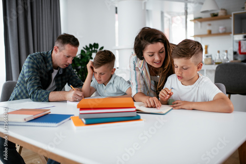 Parents helping the kids with their homework. Litlle boys learning at home..