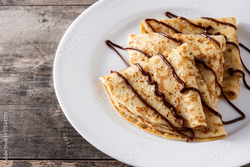 Sweet crepes with chocolate on wooden table	