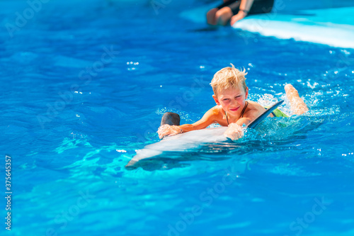 Happy little boy swimming with dolphins in Dolphinarium
