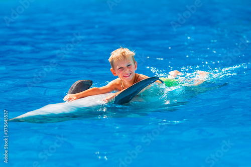 Happy little boy swimming with dolphins in Dolphinarium