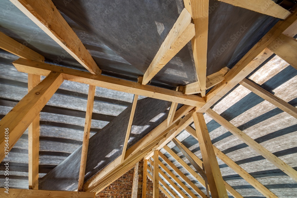 Attic of a building under construction with wooden beams of a roof structure and brick walls. Attic of a building under construction with wooden beams of a roof structure and brick walls.
