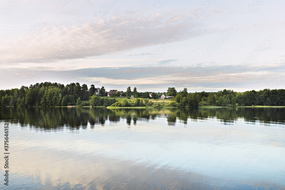 Obraz premium Village by the lake. Reflection of the sky and houses in the water. Sunset