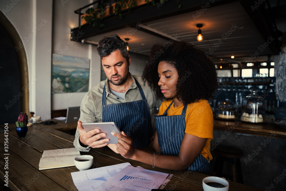 Φωτογραφία Concerned male and female coffee shop owners scrolling on tablet in rustic coffee shop