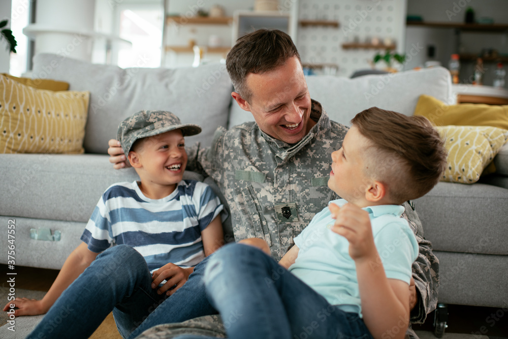 Happy soldier sitting on the floor with his family. Soldier enjoying at home with children.. Happy soldier sitting on the floor with his family. Soldier enjoying at home with children..