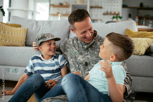 Happy soldier sitting on the floor with his family. Soldier enjoying at home with children..