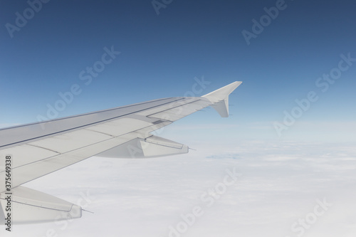 wing of an airplane that is in the air, the sky is clear with clouds in the day photo