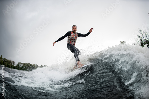 Active man in black swimsuit rides through the waves on water board © fesenko