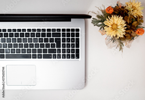 Hardworking freelancer office, with flowers and laptop, top view, flat lay