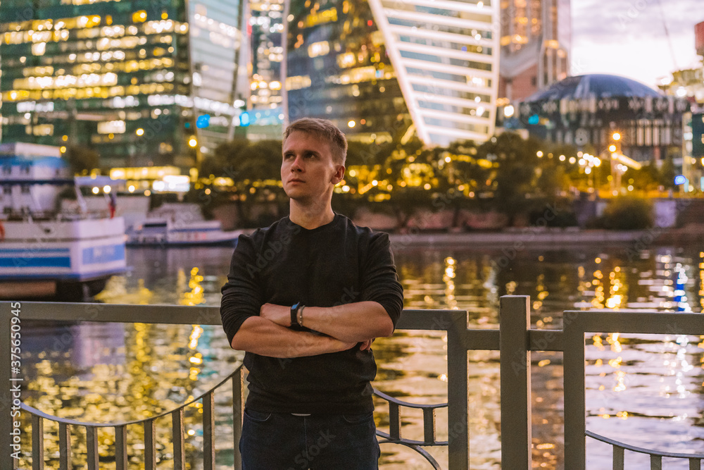 Portrait of a business man in a black sweater with a view of the night illumination business skyscrapers in Moscow Portrait of a business man in a black sweater with a view of the night illumination business skyscrapers in Moscow
