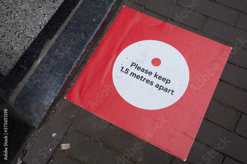 Red sticker on pavement 'Please keep 1.5 meter apart' in front of the threshold at the entrance of a shop. Coronavirus measures and Dutch government rules for social distancing photo
