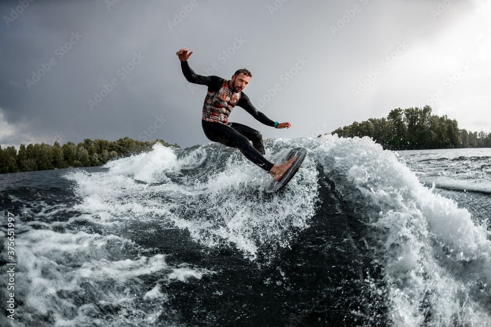 Male wakesurfer having fun rides wave on surfboard in the summer day Male wakesurfer having fun rides wave on surfboard in the summer day