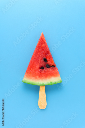 Creative food health diet concept photo of sliced watermelon fruit on stick as ice cream popsicle on blue background.