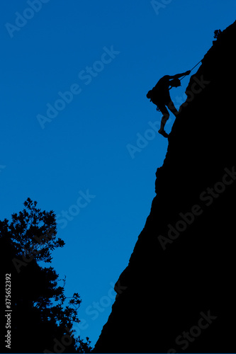 silhouette of a climber on a cliff and blue sky