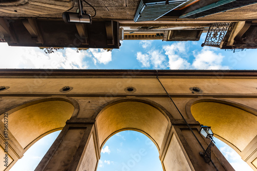 Florence, Italy orange yellow colorful building on street called Lungarno degli Acciaiuoli in Tuscany with wide low angle view of arch architecture looking up blue sky