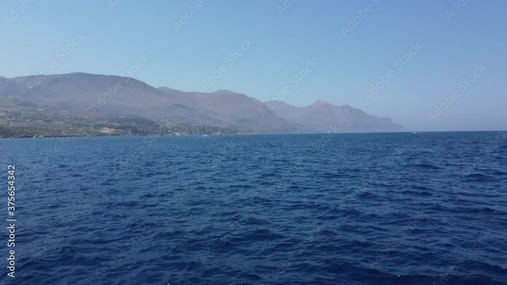 Ascend aerial shot view from yacht to the wide ocean and mountain landscape in background in Italy. Ascend aerial shot view from yacht to the wide ocean and mountain landscape in background in Italy.
