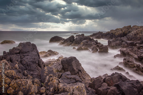 Rocky scottish coastline on a stormy day. Dark clouds and dark rocks looking out to sea