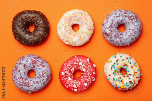 Flat lay with tasty donuts on orange background