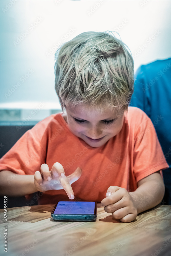 Happy boy interest look on smartphone screen. Phone as development education or degradation, absorb game habit obsession, live virtual world, danger of internet, loss parental control concept Happy boy interest look on smartphone screen. Phone as development education or degradation, absorb game habit obsession, live virtual world, danger of internet, loss parental control concept